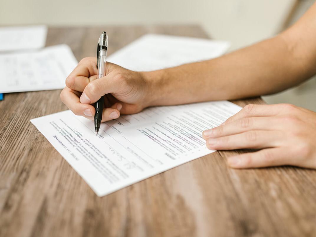 Iemand schrijft op een papier met uitgetypte tekst